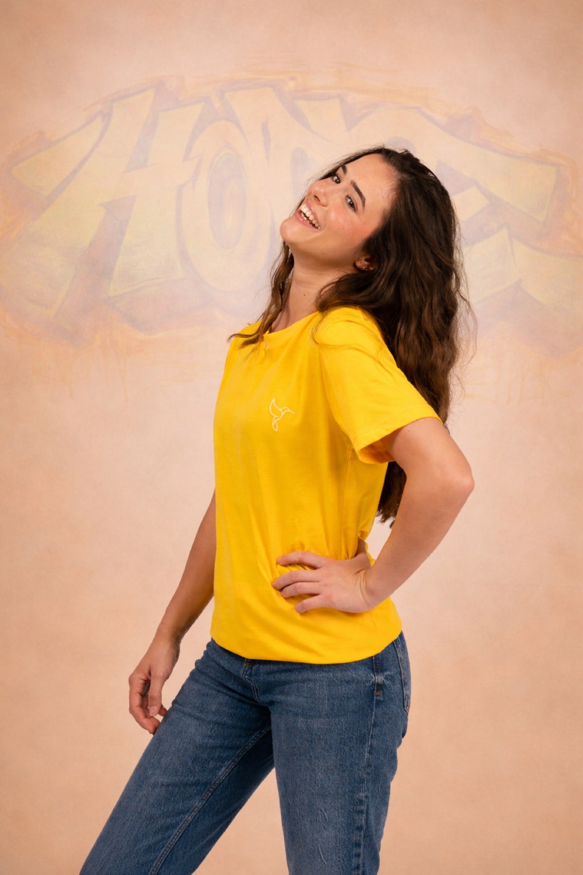 Warrior Sol Sunshine Yellow Everyday T-Shirt campaign photo with HOPE graffiti art backdrop and hummingbird logo