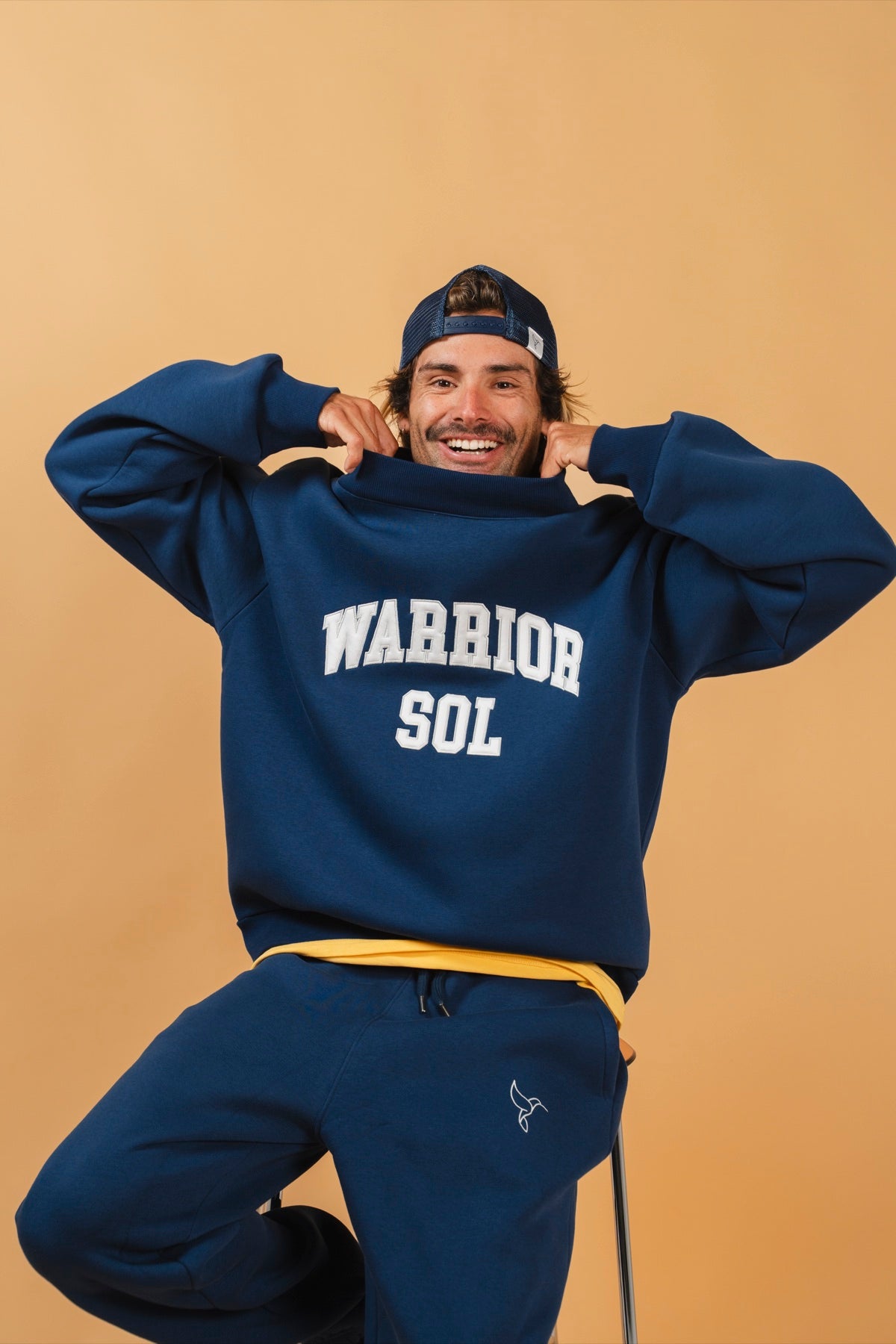 Varsity Mockneck in Midnight Blue — model wearing midnight blue varsity mockneck with WARRIOR SOL lettering in gold | Warrior Sol cancer support apparel