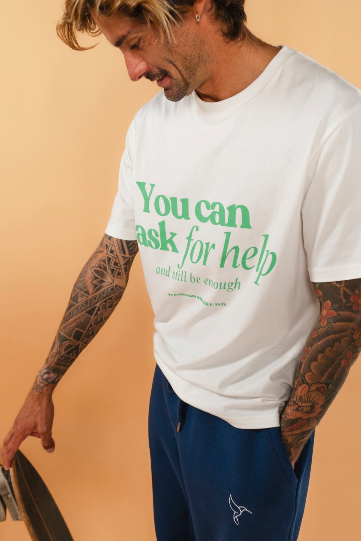 Warrior Sol Brave Series - You Can Ask For Help And Still Be Enough - male model wearing Coconut White t-shirt with green lettering, warm gold campaign background