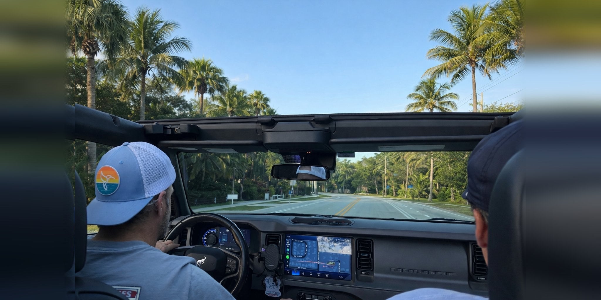 Bronco driving through palm trees with Warrior Sol sky blue hat