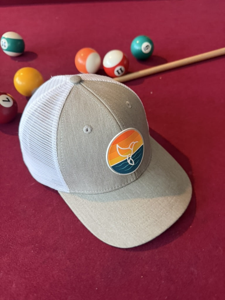 Warrior Sol Hummingbird Sunrise 6-panel trucker hat, Moon + Snow colorway, front view with the sunset whale-tail patch