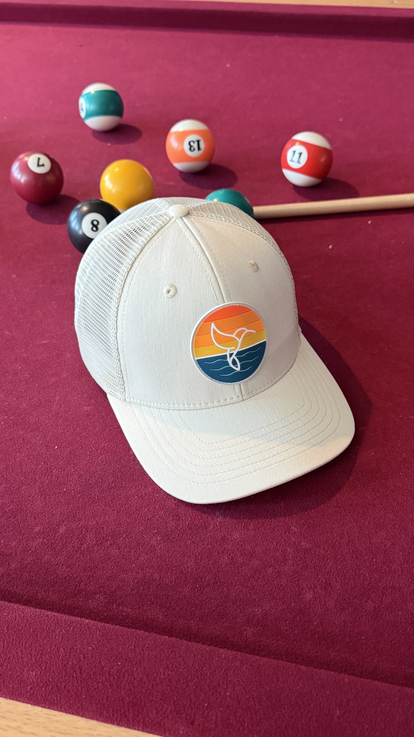Warrior Sol Hummingbird Sunrise 6-panel trucker hat, Sand + Shell colorway, front view with the sunset whale-tail patch