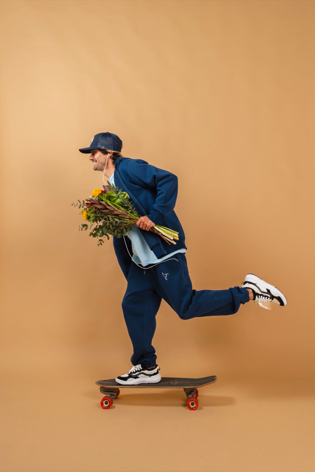 Warrior Sol ShieldUp Zip-Up Hoodie in Midnight Blue model skateboarding with flowers gold campaign background